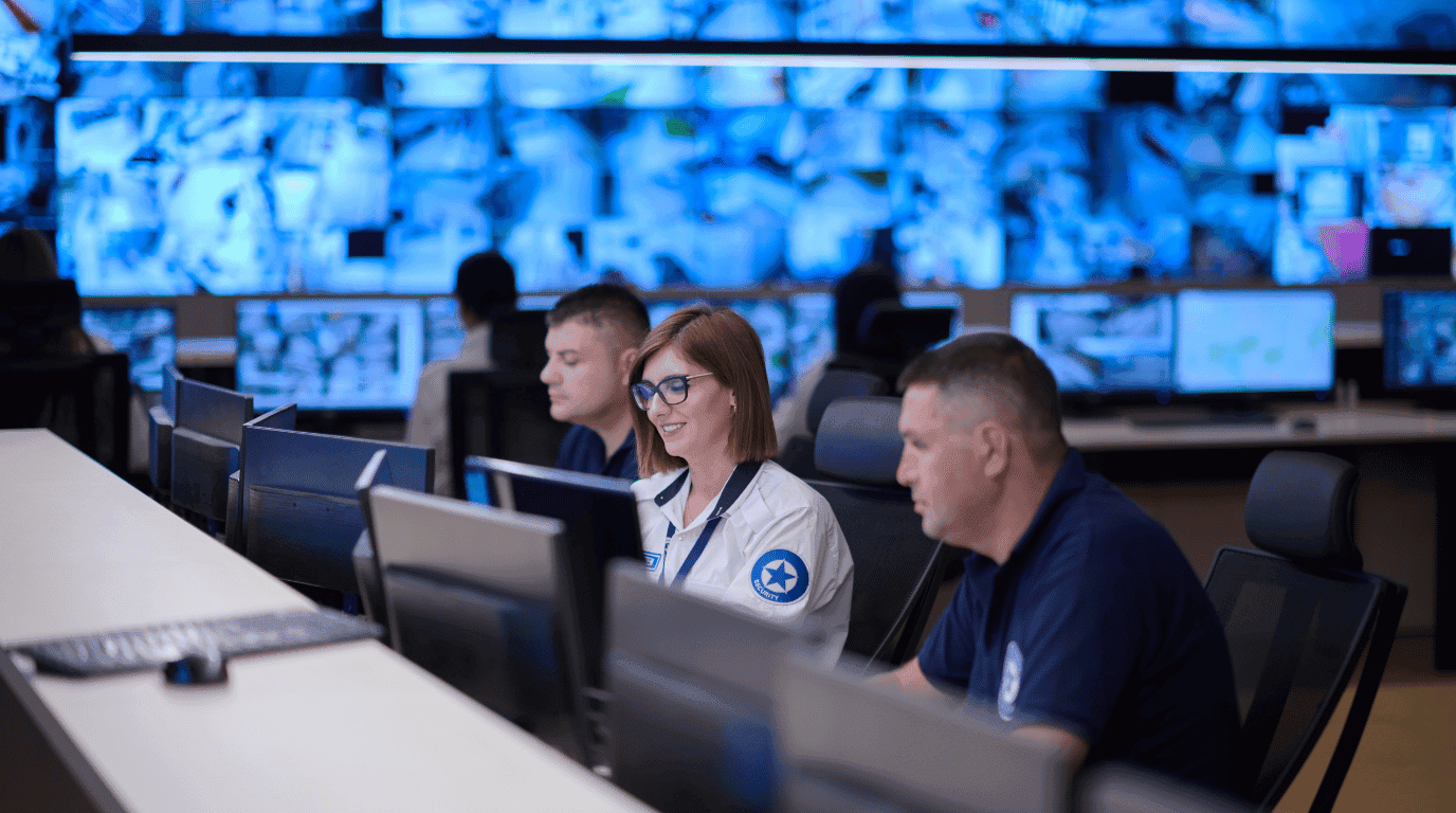 Security operations team monitoring live feeds on a wall of screens in a control room