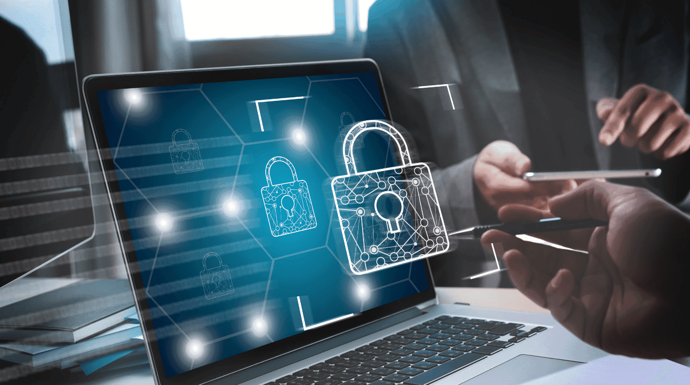 Laptop screen showing padlock icons linked across a network, reviewed by two colleagues at a desk